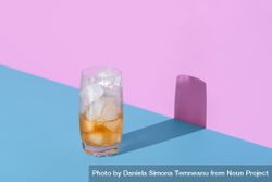 Ice tea glass, half empty, minimalist on a vibrant colored background 4AZgRb