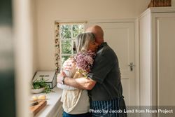 Older man hugging his wife standing in kitchen 0WP915