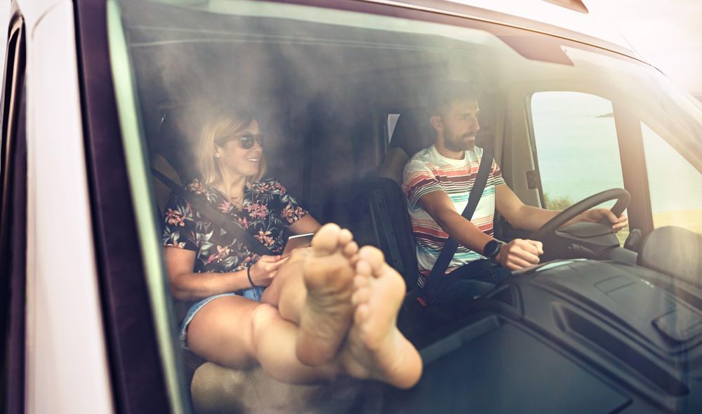 Male driving a motorhome with female in passenger seat with feet up