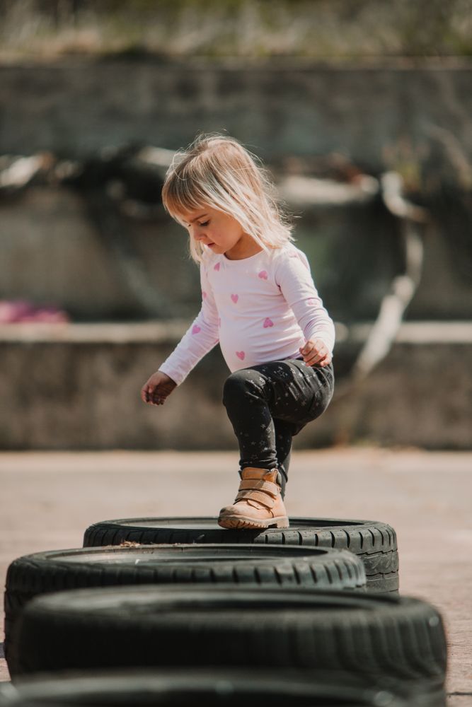 Cute girl walking on car tires