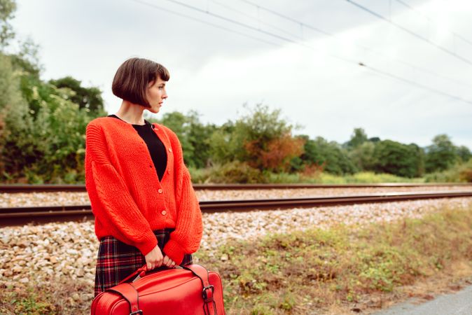 Woman looking at approaching modern train on railroad