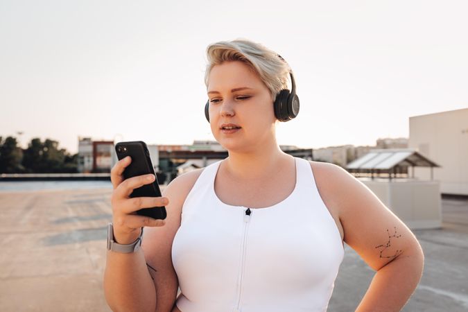 Woman in exercise gear and headphones checking her phone