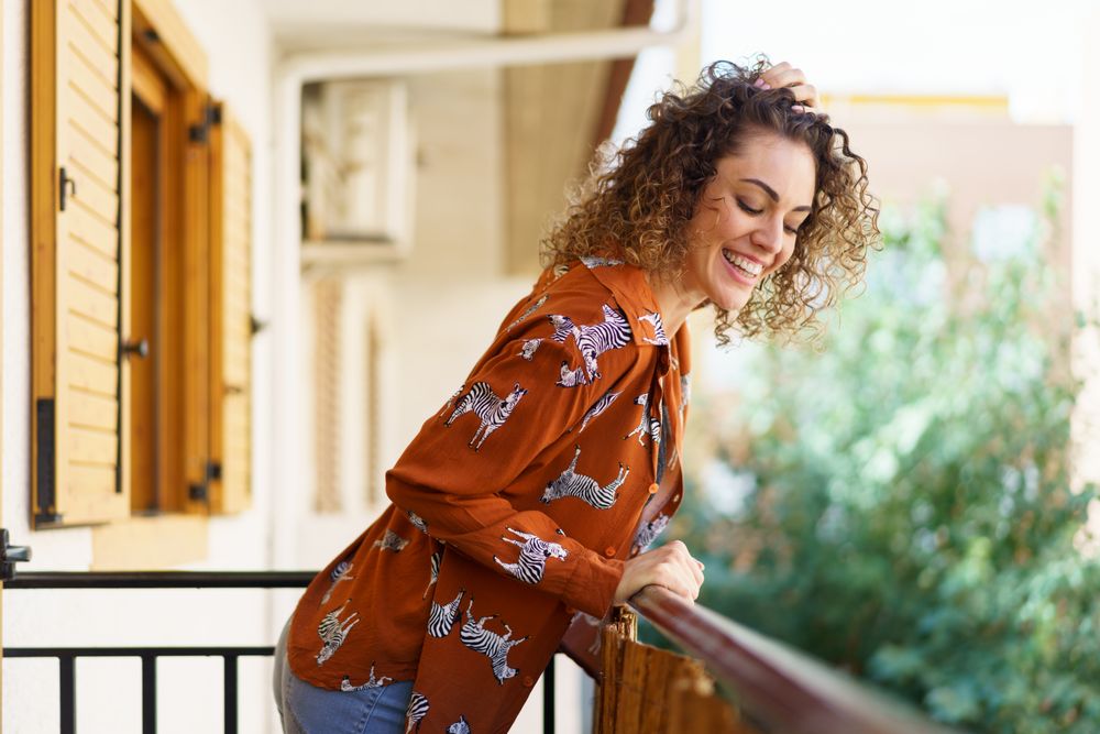 Happy woman smiling down to street from her balcony