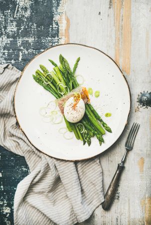 Asparagus and soft boiled egg on plate, on wooden table, with linen