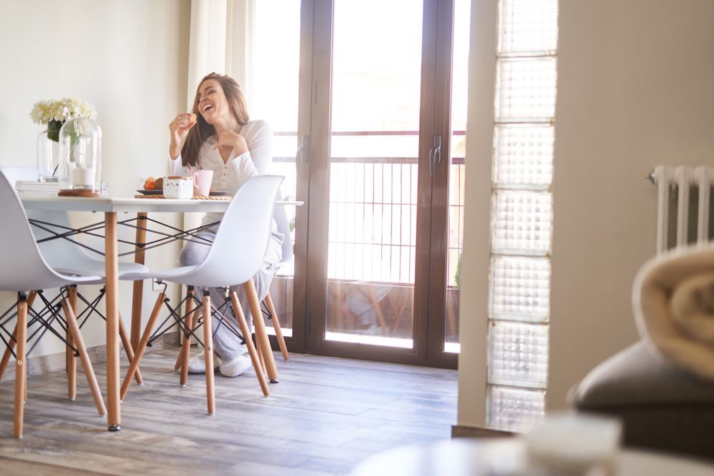 Smiling woman eating at table at home