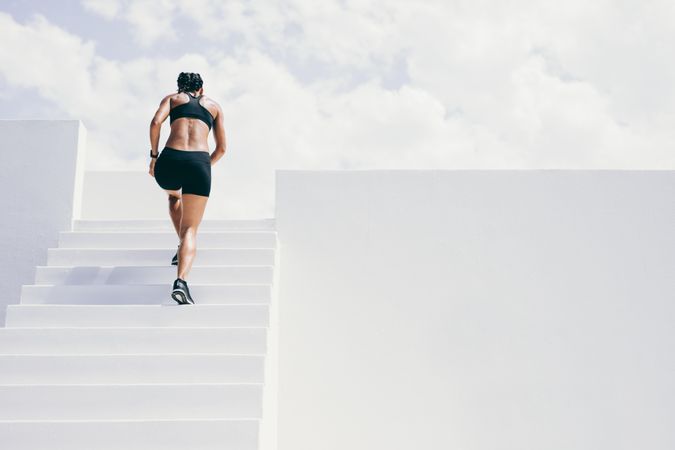 Rear view of a female athlete running up stairs of a building