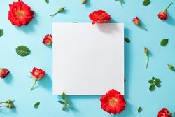 Creative arrangement of red flowers and leaves on pastel blue background with paper card note