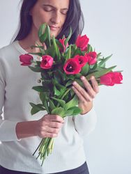 Brunette lady smelling bouquet of red tulips