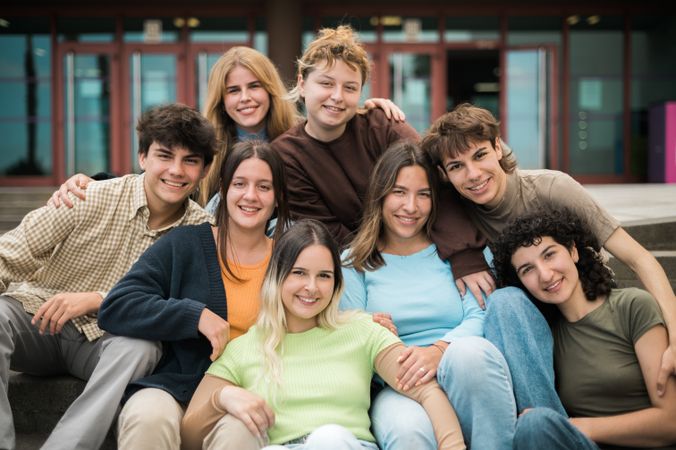 Delighted young friends cuddling and smiling at camera on street