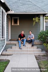 Portrait of two men sit on a porch smiling at the camera 4AzZqb