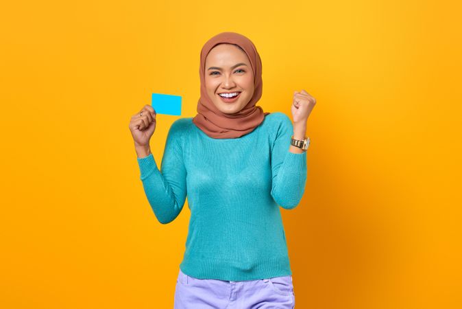 Muslim woman looking like she won while holding credit card