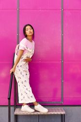 Female in floral overalls standing on stoop by pink trailer