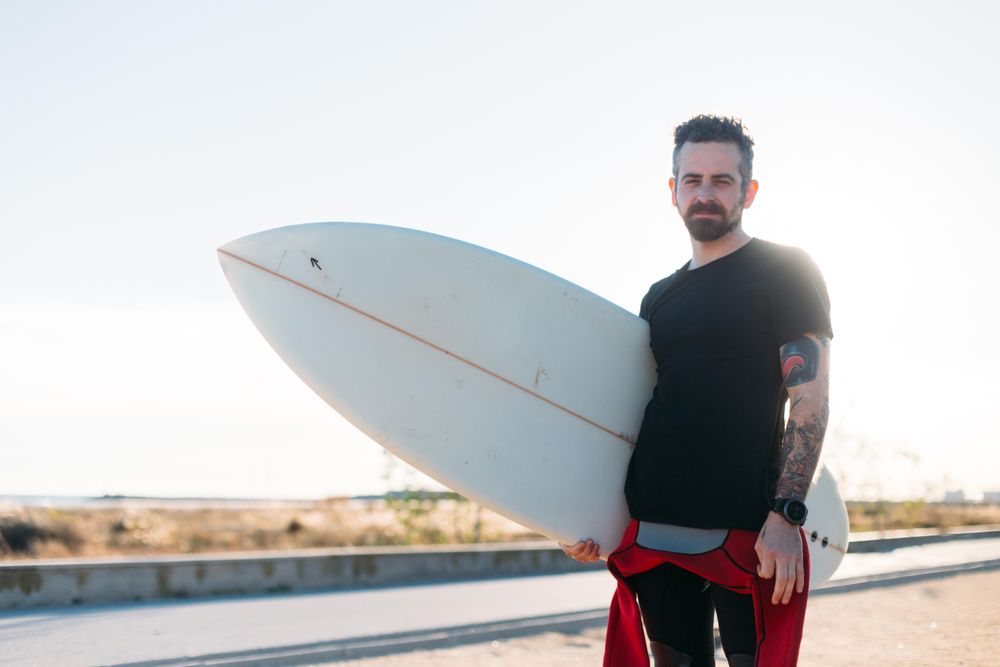 Man standing on road with surfboard