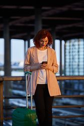 Smiling young woman browsing on phone at station