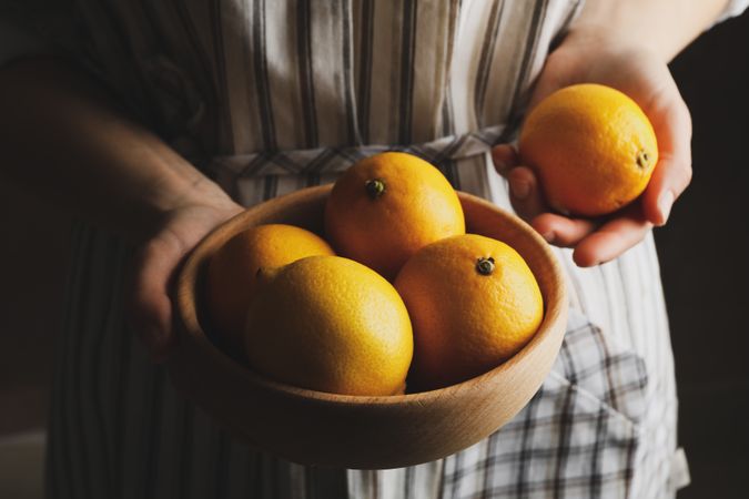 Woman holds bowl with lemons. Ripe fruit