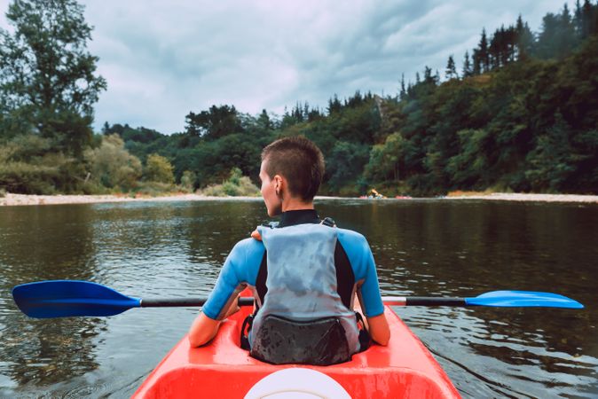 Female kayaking with paddle in raised hands