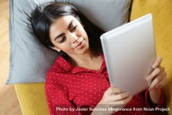 Female relaxing on sofa while reading a tablet 5zqZX0