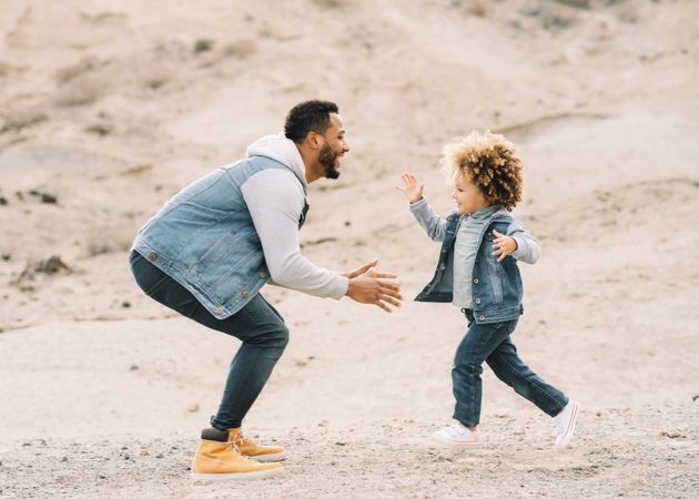 Black father playing with child on ground
