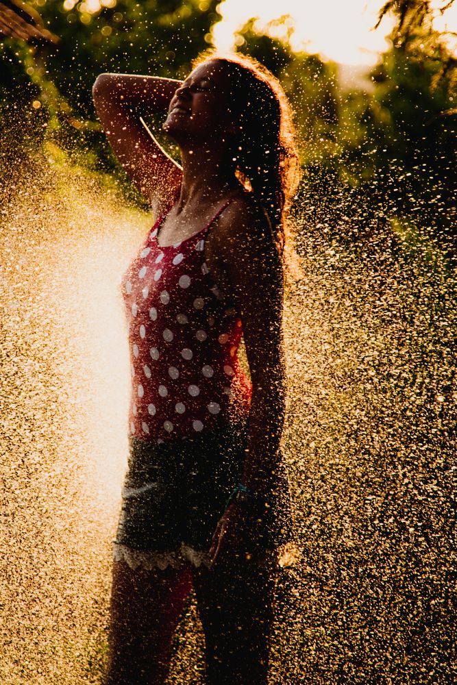 Cheerful teenager having fun with jet of water
