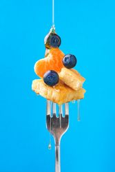 Appetizing fruit dessert with honey on fork