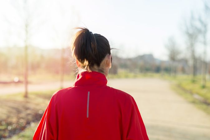 Back of woman walking outdoors on sunny day