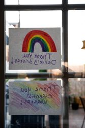 Reverse view of two handmade signs from within a house thanking essential workers