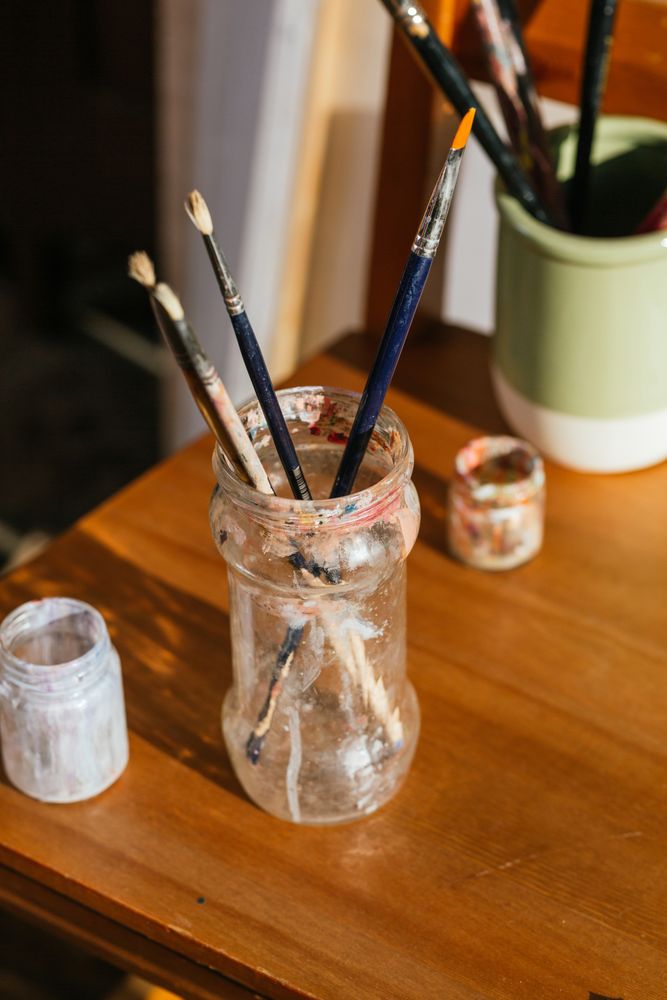 Paintbrushes in glass jar on table