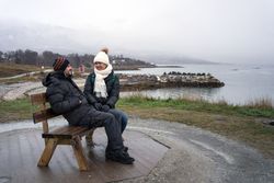Tourists relaxing on bench on elevation by sea