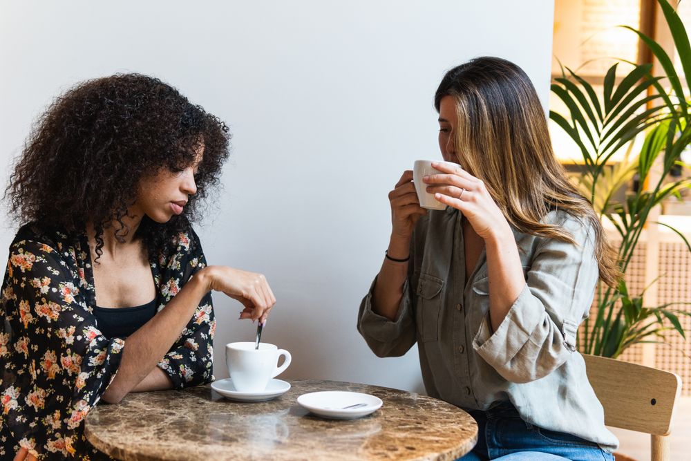 Multiethnic girlfriends with coffee spending time in cafe