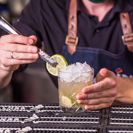 Bartender garnishing a cocktail with lime wheel