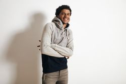 Man smiling with arms crossed in grey hoodie