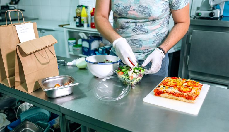 Unrecognizable cook preparing takeaway orders