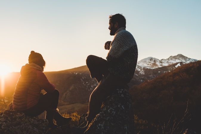 Man and woman enjoying sunset in autumn mountains
