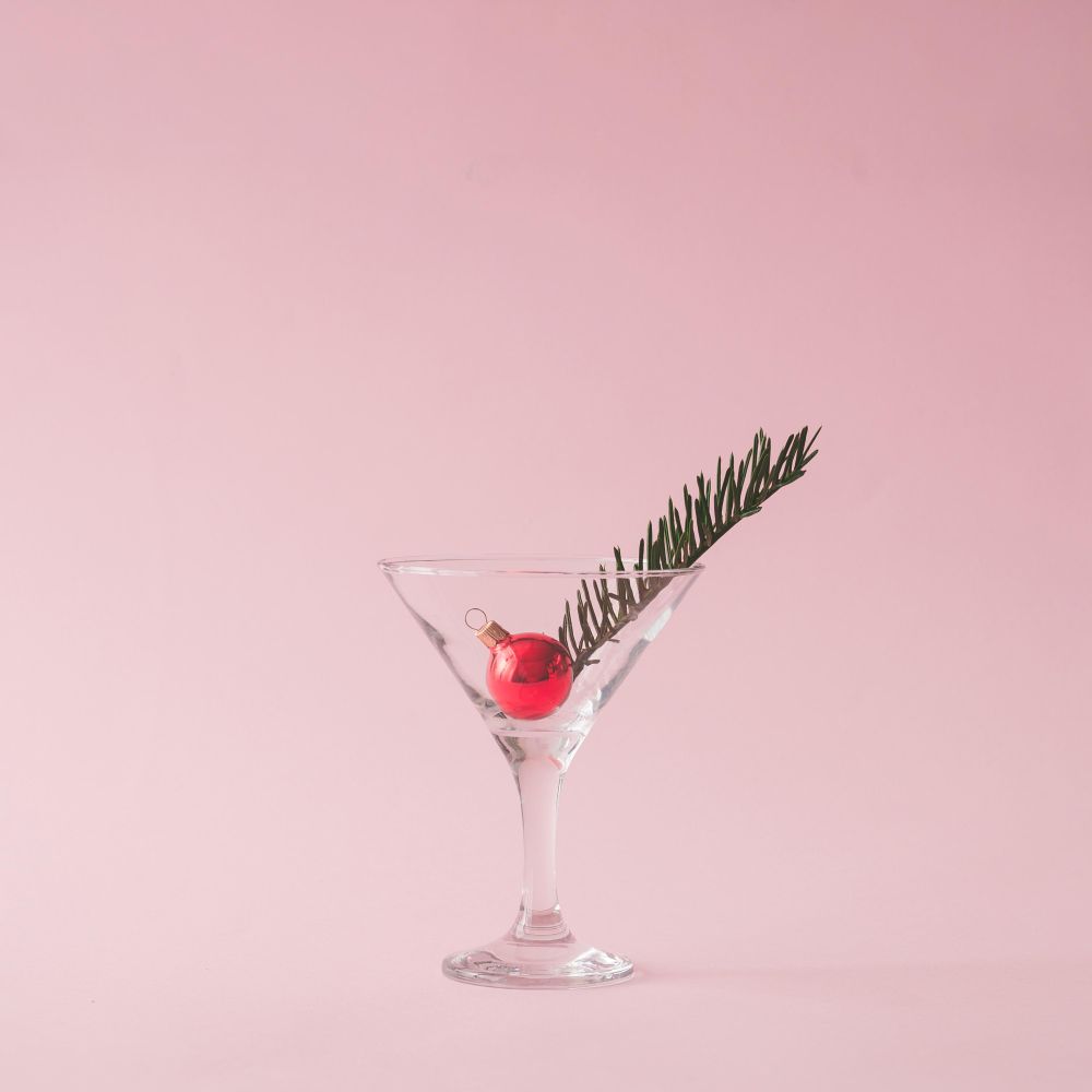 Christmas tree decoration in martini glass on pastel pink background with creative copy space