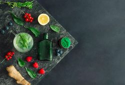 Healthy scene of spirulina powder, nettle leaves, berries, ginger on marble slap on dark background