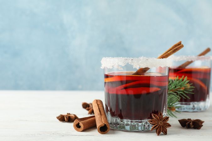 Glasses of tasty mulled wine on blue wooden background, space for text