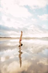 Woman doing handstand near sea