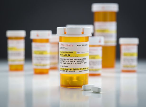 Medicine Bottles and Pills on Reflective Surface With Grey Background