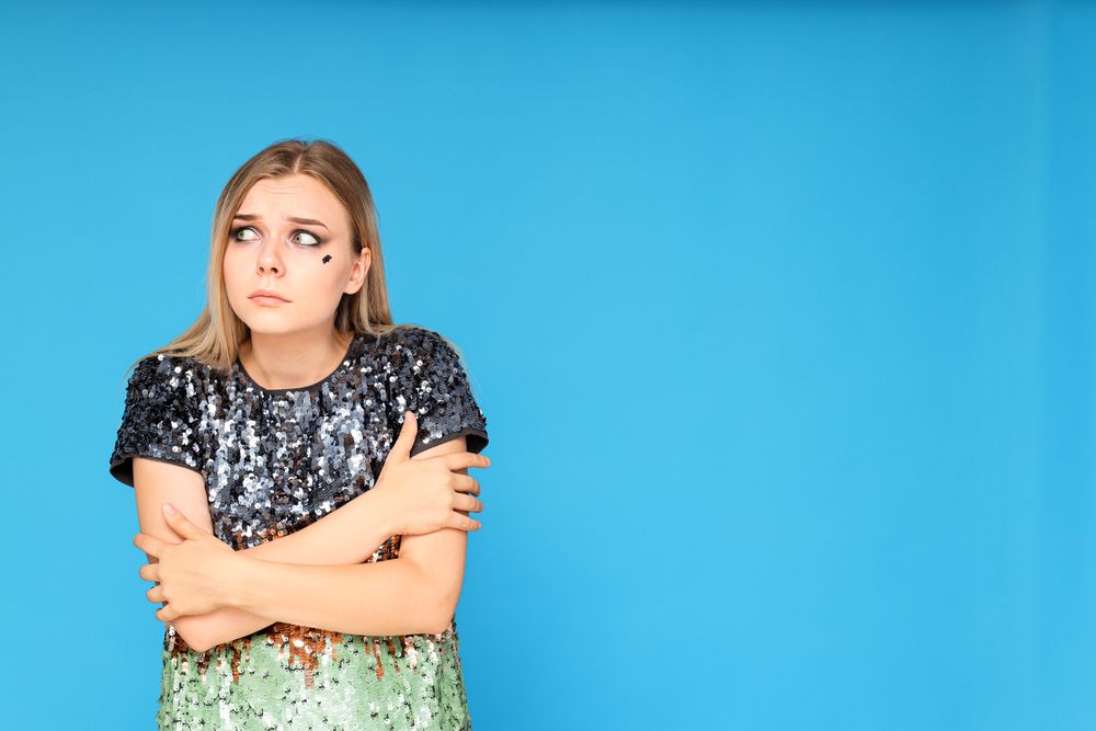 A woman in a dress with sequins, very scared, on a blue background