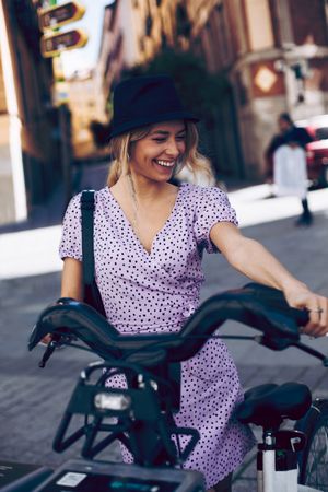 Young woman taking a rental bike in city