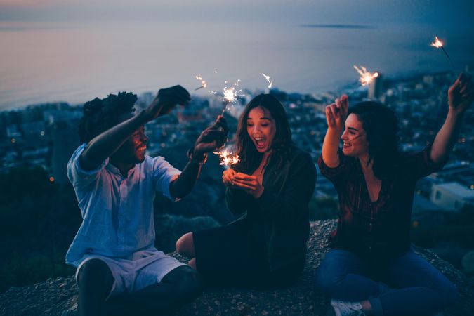 Group of friends having fun lighting sparklers in the evening