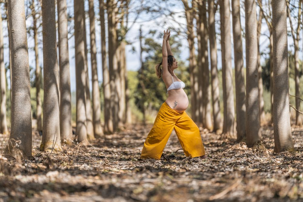 Concentrated adult expectant mother practicing yoga in park