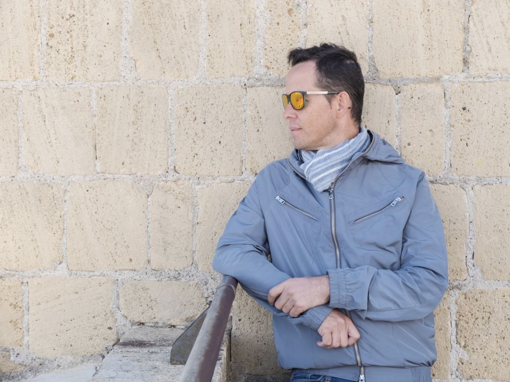 Pensive man wearing sunglasses leaning on an old balcony