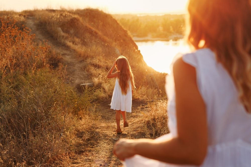 Female child in dress walking in front of mother on river walk