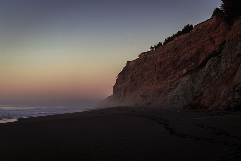Side of cliffs on foggy Pacific Ocean beach