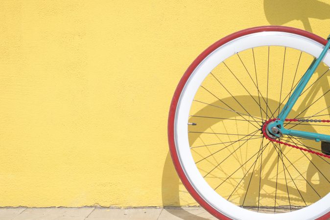 Wheel of bike outside on bright yellow wall