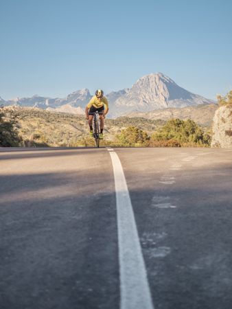 healthy man riding a bicycle on a mountain road in a sunny day