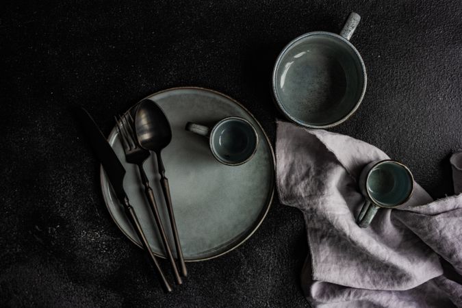 Grey table setting with dark cutlery and napkin
