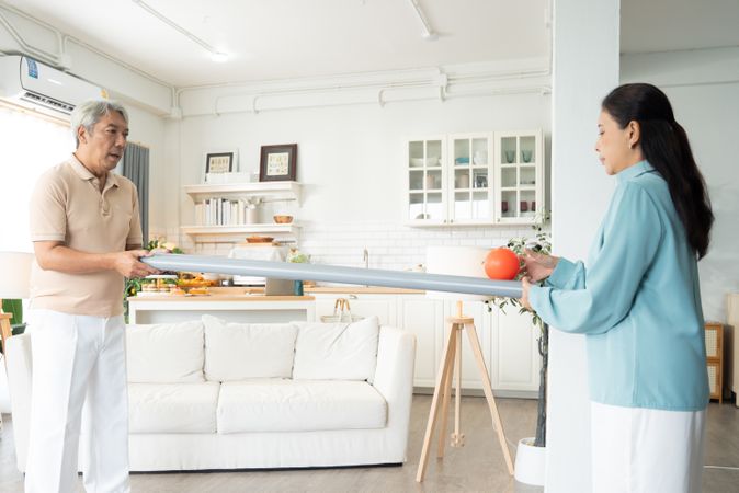 Asian mature couple playing rolling ball for practice balance and concentrate in the living room
