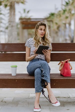 Woman sitting on bench and using tablet